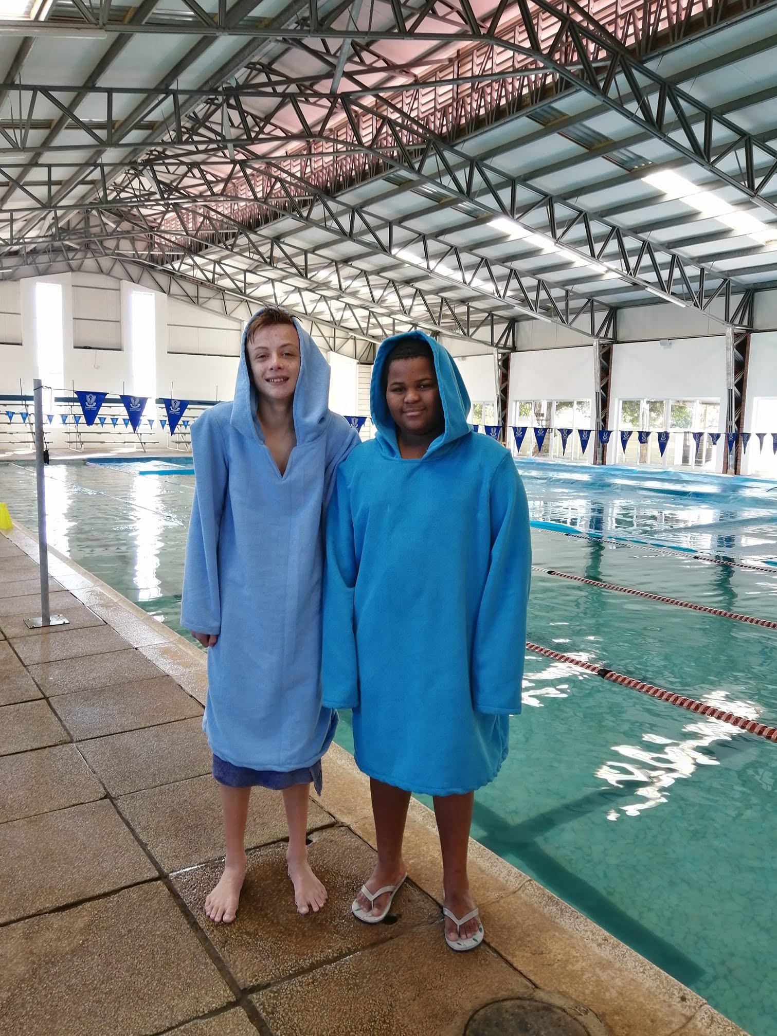 Two young Coastal Aquatics swimmers poolside at the indoor pool